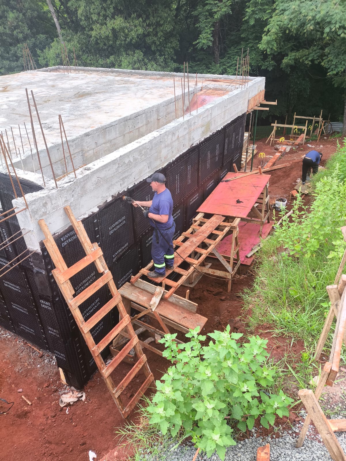 Equipe aplicando manta asfáltica em parede externa